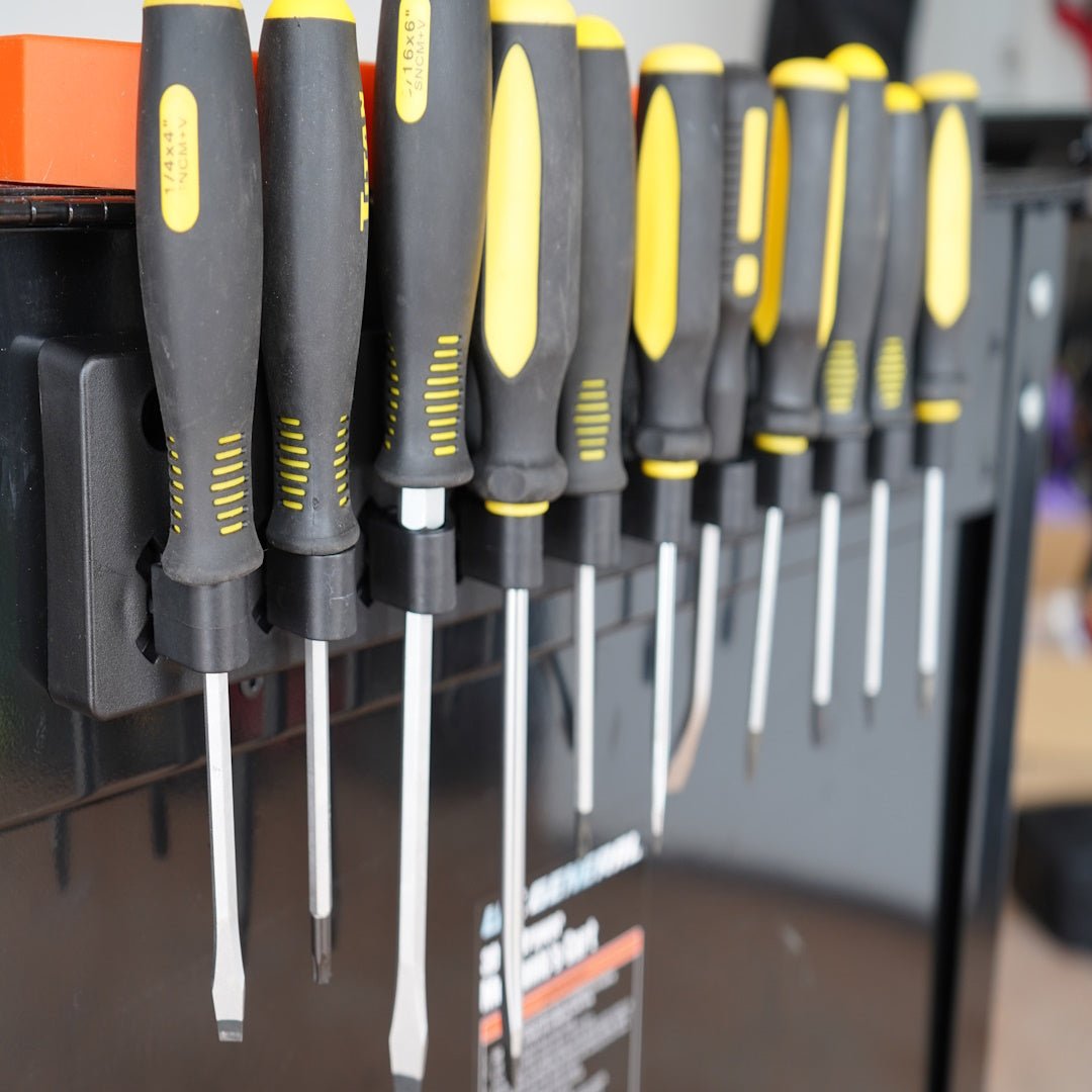 Set of screwdrivers with black and yellow handles on a magnetic tool holder.